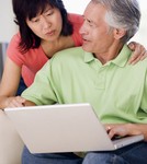 Couple in living room with laptop smiling Couple in living room with laptop smiling